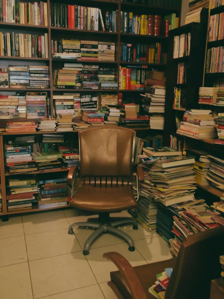 A chair in a used book store surrounded by volumes
